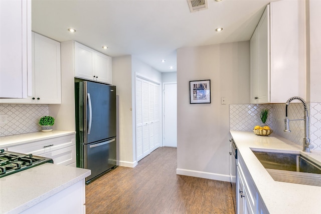 kitchen with appliances with stainless steel finishes, tasteful backsplash, sink, light hardwood / wood-style flooring, and white cabinets