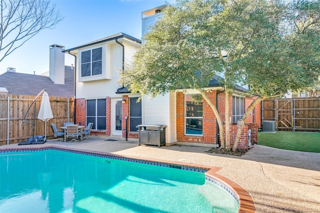 back of property featuring cooling unit, a patio area, and a fenced in pool