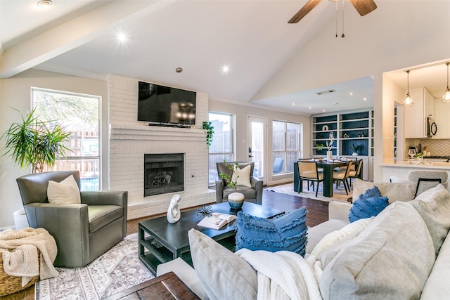 living room with ceiling fan, light wood-type flooring, high vaulted ceiling, and a brick fireplace