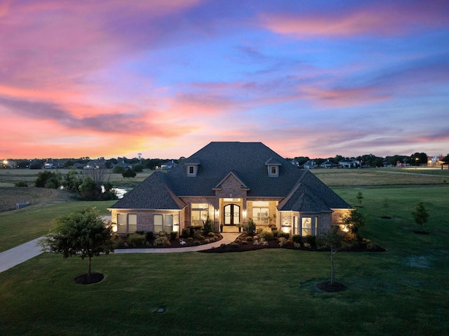 french country inspired facade featuring french doors and a front lawn