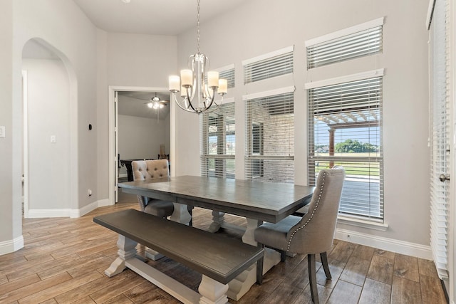 dining area with a towering ceiling and ceiling fan with notable chandelier