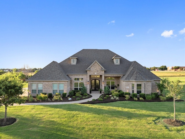 view of front of home featuring a front yard, brick siding, and roof with shingles