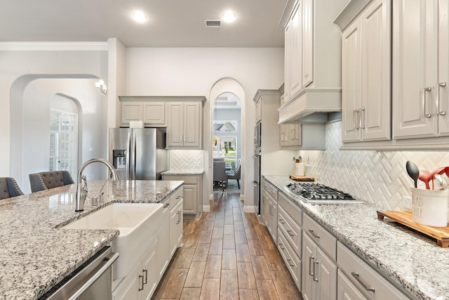 kitchen with appliances with stainless steel finishes, light stone counters, a kitchen breakfast bar, and sink