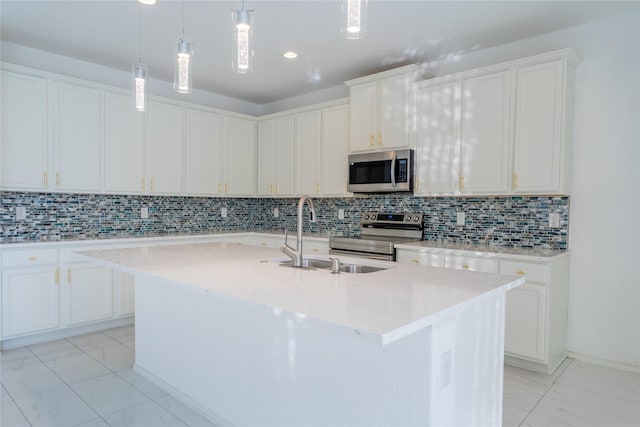 kitchen featuring a center island with sink, light countertops, decorative backsplash, appliances with stainless steel finishes, and a sink