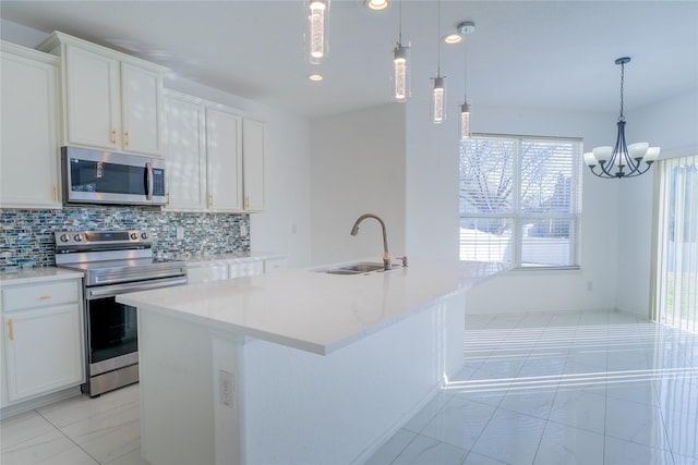 kitchen featuring decorative backsplash, an island with sink, stainless steel appliances, white cabinetry, and a sink