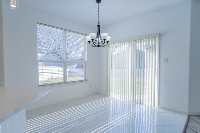 unfurnished dining area featuring an inviting chandelier and baseboards