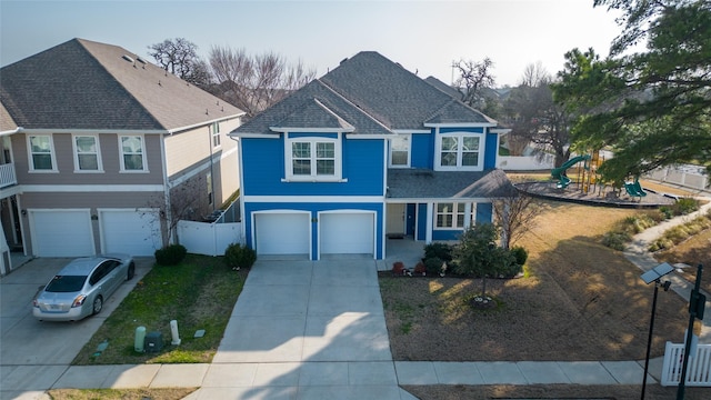 view of front of property featuring concrete driveway, roof with shingles, an attached garage, fence, and a playground