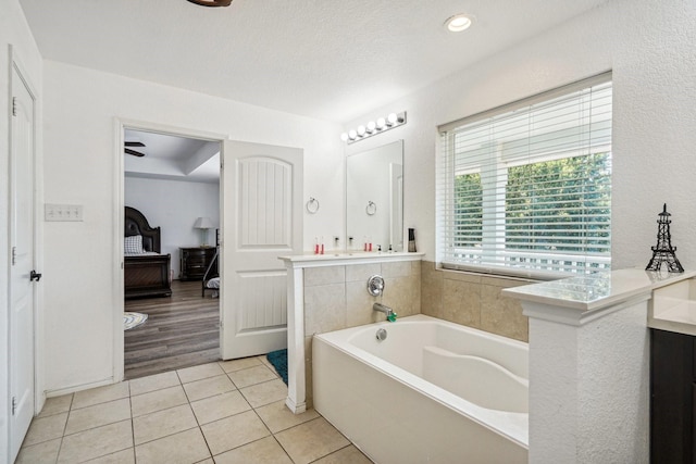 bathroom with tile patterned flooring, a textured ceiling, vanity, and a tub