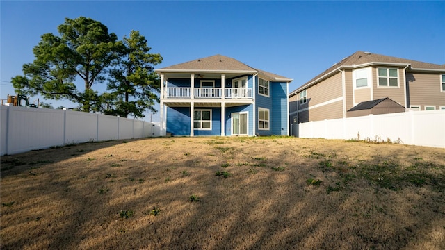 rear view of house featuring ceiling fan, a fenced backyard, and a balcony