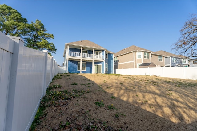 back of property with a balcony and a fenced backyard