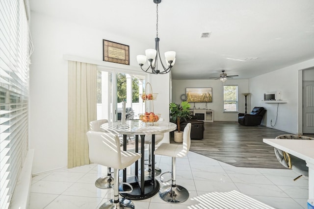 dining space featuring ceiling fan with notable chandelier