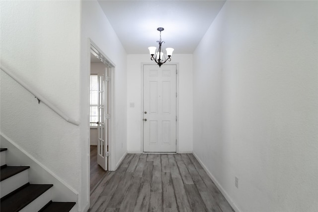 entrance foyer featuring a chandelier, stairway, baseboards, and wood finished floors