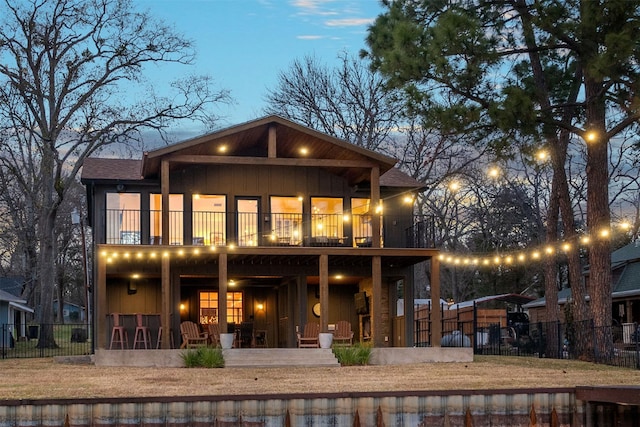 back house at dusk featuring a balcony and a patio