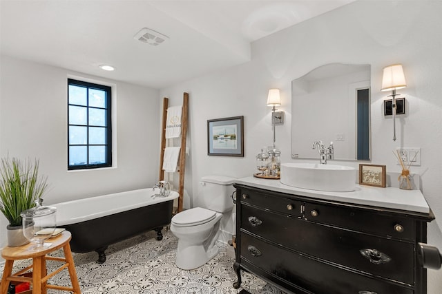 bathroom featuring tile patterned flooring, vanity, toilet, and a tub to relax in