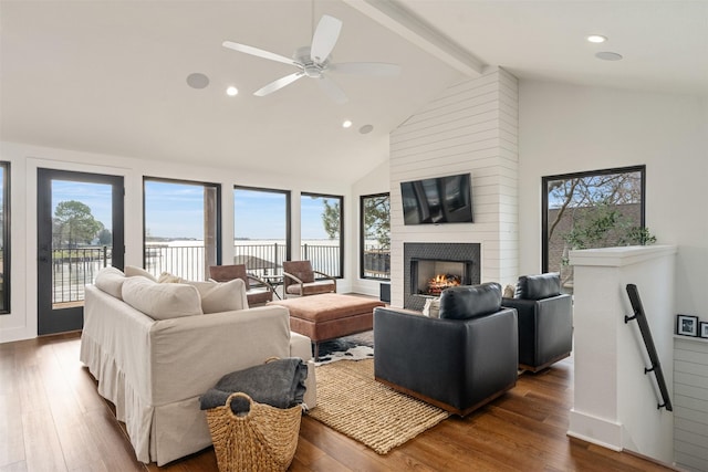 living room featuring beam ceiling, a large fireplace, plenty of natural light, and hardwood / wood-style floors