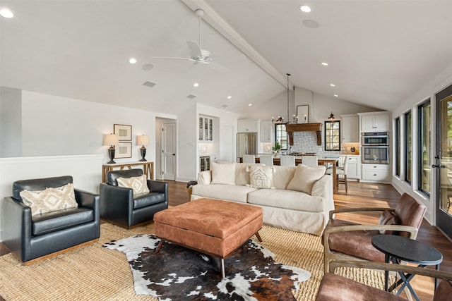 living room featuring vaulted ceiling with beams, light wood-type flooring, plenty of natural light, and ceiling fan