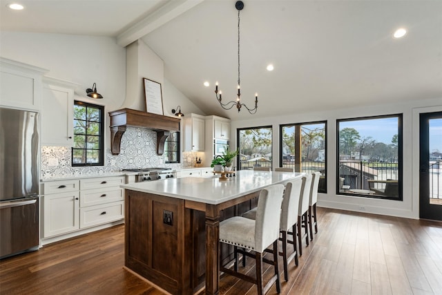 kitchen featuring stainless steel refrigerator, a center island, tasteful backsplash, decorative light fixtures, and white cabinets