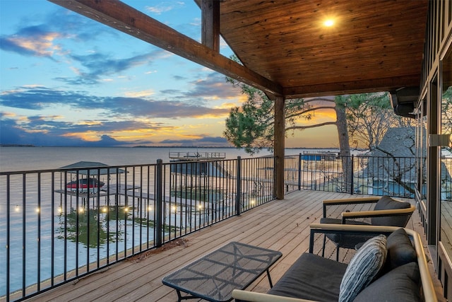 deck at dusk featuring a water view