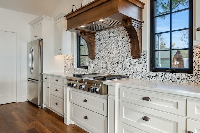 kitchen with a healthy amount of sunlight, white cabinetry, stainless steel appliances, and premium range hood