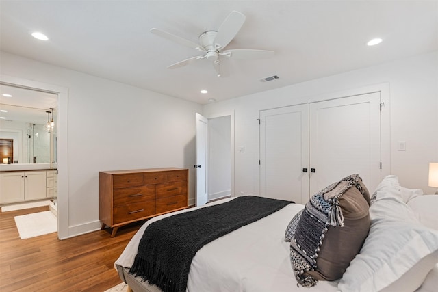 bedroom featuring ceiling fan, ensuite bath, wood-type flooring, and a closet