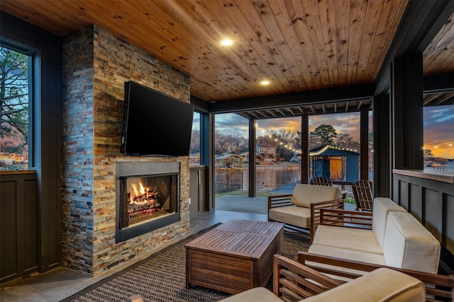 sunroom featuring an outdoor stone fireplace, a healthy amount of sunlight, and wood ceiling