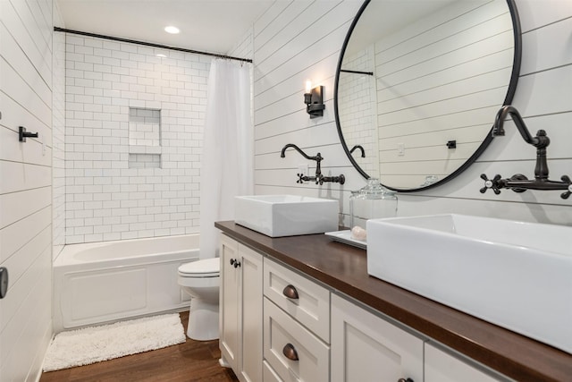 full bathroom featuring hardwood / wood-style floors, vanity, shower / tub combo, and toilet