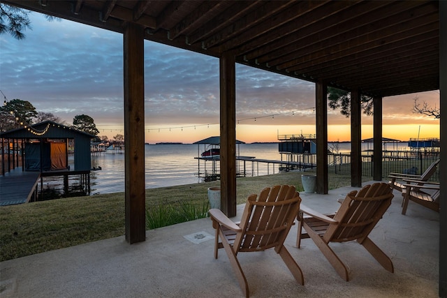 patio terrace at dusk featuring a dock and a water view