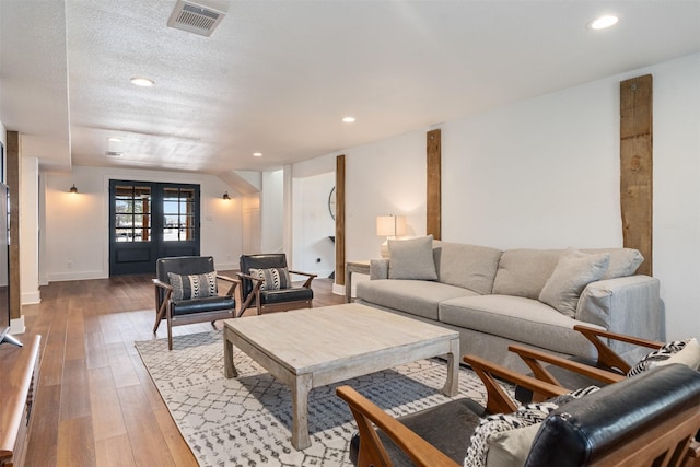 living room with wood-type flooring, a textured ceiling, and french doors