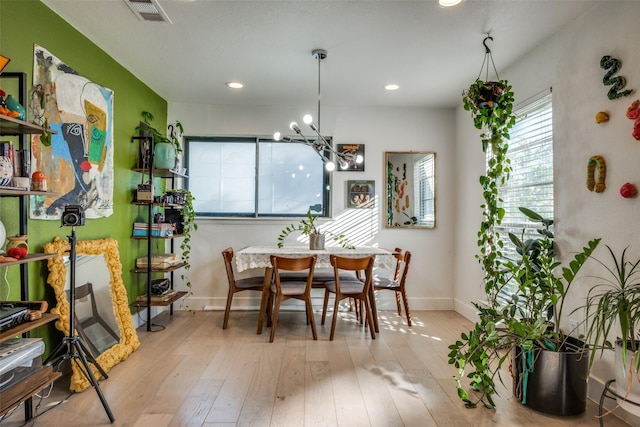 dining area with an inviting chandelier and light hardwood / wood-style flooring