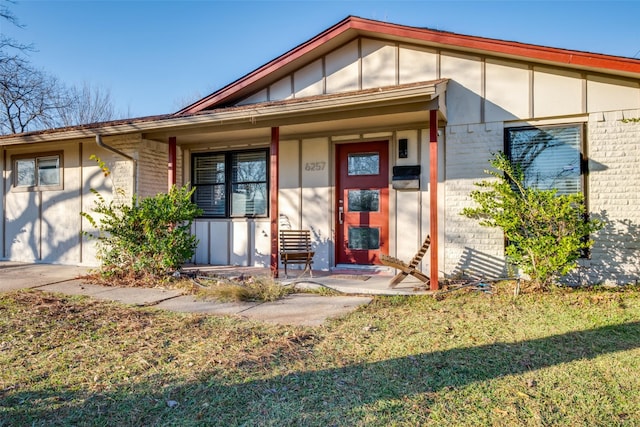 doorway to property with a lawn and covered porch