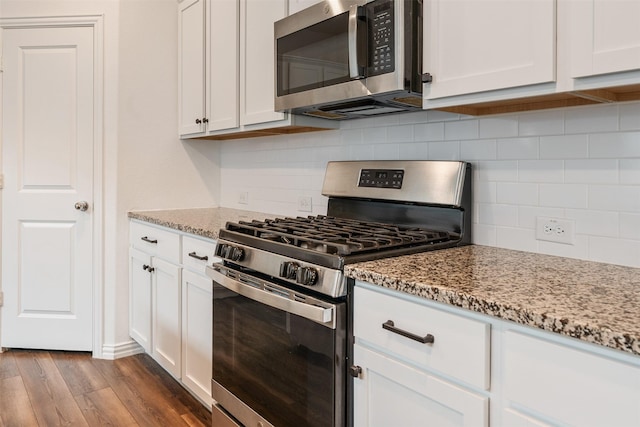 kitchen with light stone counters, appliances with stainless steel finishes, and white cabinets