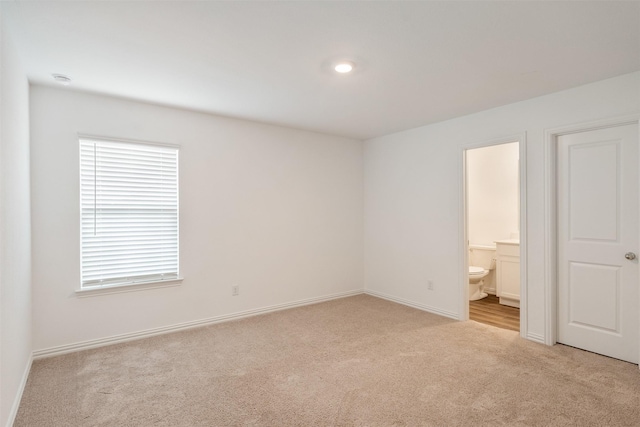 unfurnished bedroom featuring ensuite bathroom and light carpet