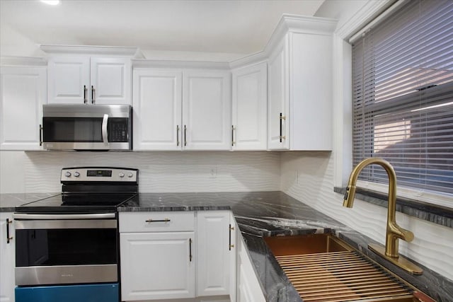 kitchen with appliances with stainless steel finishes, sink, white cabinets, and decorative backsplash