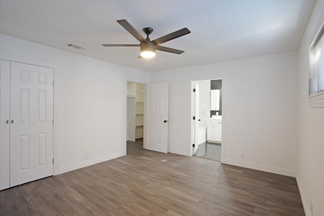 unfurnished bedroom with dark wood-type flooring, connected bathroom, and ceiling fan