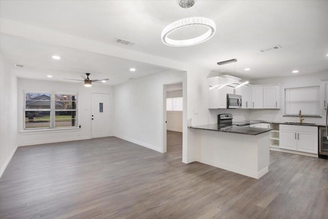 kitchen featuring white cabinetry, sink, hanging light fixtures, hardwood / wood-style flooring, and stainless steel appliances