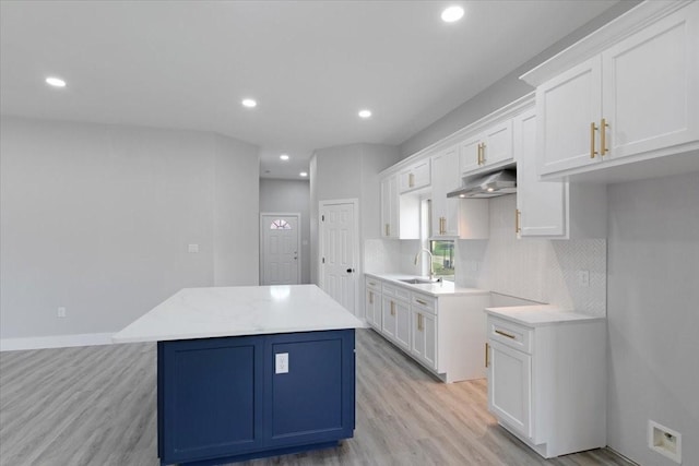 kitchen featuring white cabinets, sink, a kitchen island, and light hardwood / wood-style flooring