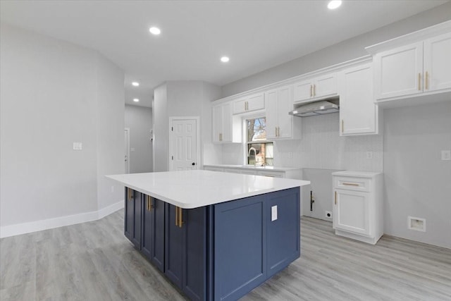 kitchen with backsplash, blue cabinetry, a center island, light hardwood / wood-style floors, and white cabinetry