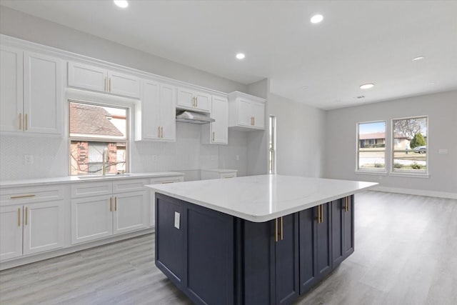 kitchen featuring white cabinetry, a center island, sink, and backsplash