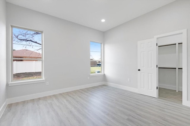 unfurnished bedroom featuring light hardwood / wood-style floors, a walk in closet, and a closet