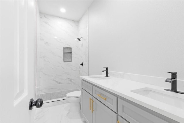 bathroom with a tile shower, vanity, and toilet