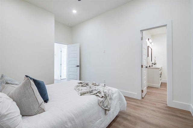 bedroom with ensuite bathroom and light hardwood / wood-style flooring