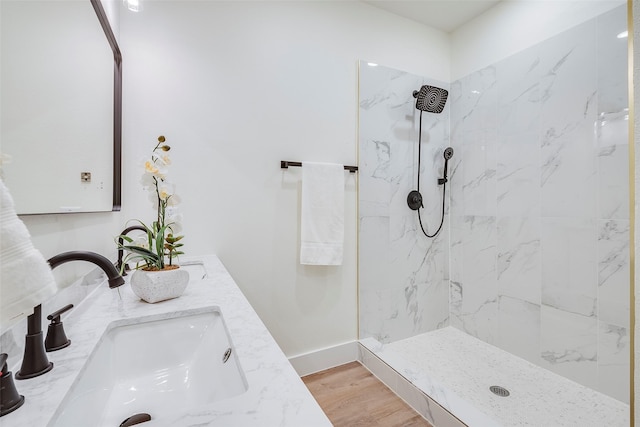 bathroom with vanity, a tile shower, and wood-type flooring