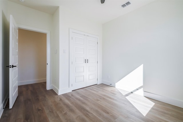 unfurnished bedroom with ceiling fan, a closet, and hardwood / wood-style flooring