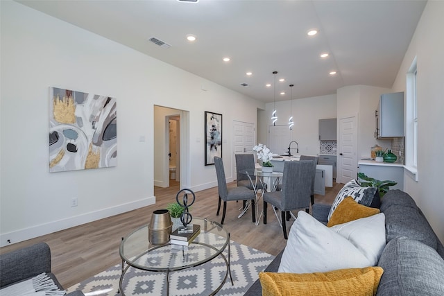 living room featuring lofted ceiling and light hardwood / wood-style flooring