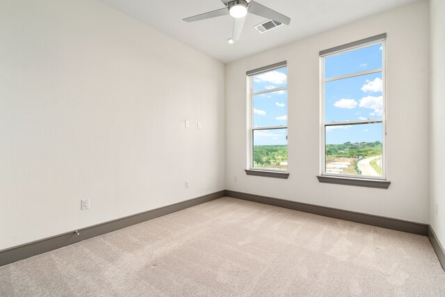 spare room with a wealth of natural light, ceiling fan, and light colored carpet