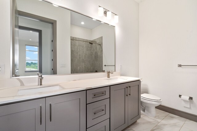 bathroom with a tile shower, vanity, and toilet