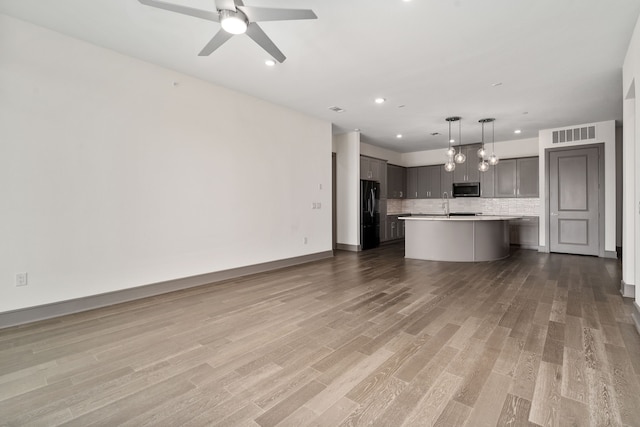 unfurnished living room featuring ceiling fan, wood-type flooring, and sink