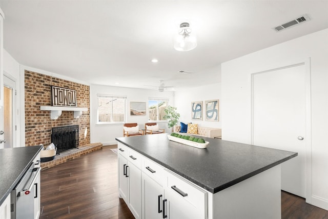 kitchen featuring dark hardwood / wood-style flooring, ceiling fan, a fireplace, a center island, and white cabinetry