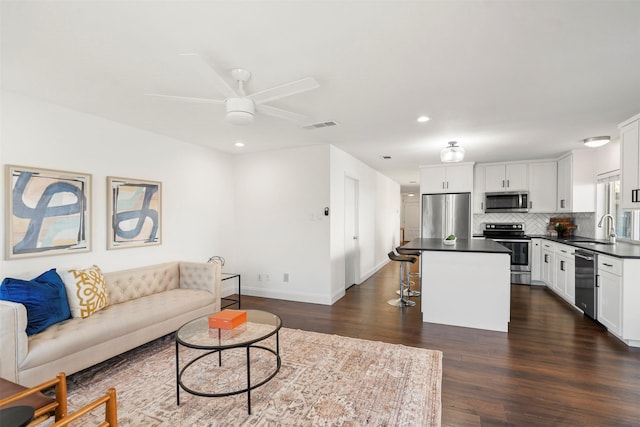 living room featuring ceiling fan, dark hardwood / wood-style floors, and sink