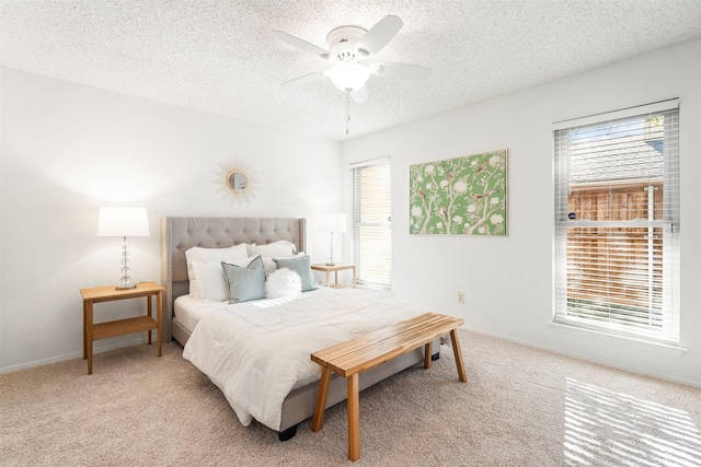 bedroom with multiple windows, ceiling fan, light carpet, and a textured ceiling